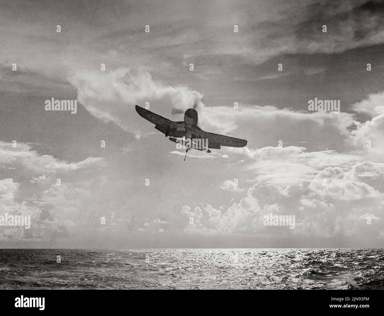 Silhouette di un Corsair Chance-Vought come lei entra a terra a bordo di HMS Illustrious mentre lei sta navigando nell'Oceano Indiano. L'americano Vought F4U Corsair è stato progettato e gestito come un aereo da caccia basato su vettore, che ha visto il servizio nella seconda guerra mondiale Nel 1943, la Royal Navy ricevette il suo primo lotto di 95 Vought F4U-1s, data la denominazione 'Corsair [Mark] i'. Con i primi squadroni furono assemblati e addestrati sulla costa orientale degli Stati Uniti. Foto Stock