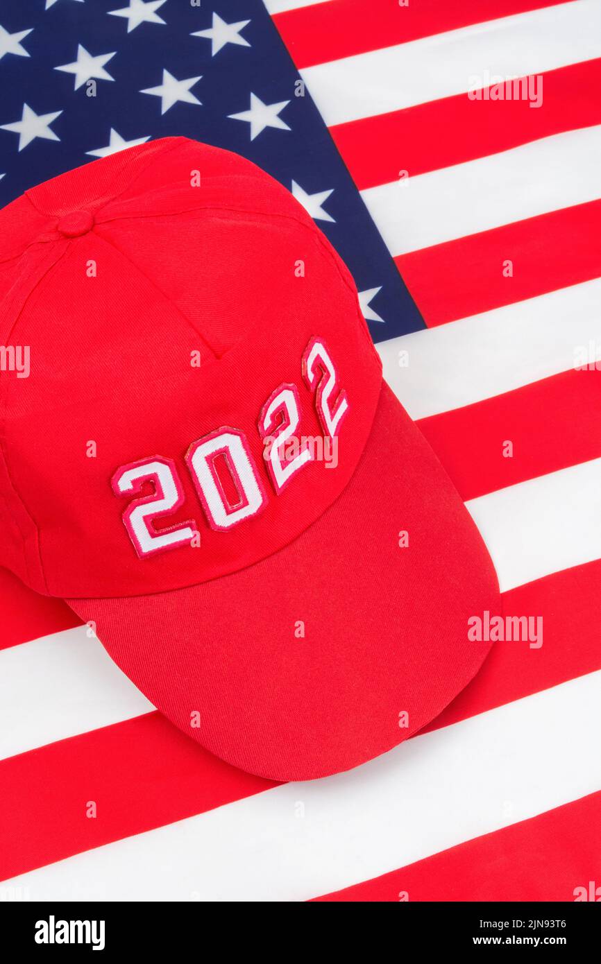 Cappello rosso TIPO MAGA con data 2022 sulla bandiera delle stelle e delle strisce degli Stati Uniti. Per le vittorie repubblicane in 2022 elezioni di Midterm degli Stati Uniti in novembre & Red Wave repubblicano degli Stati Uniti Foto Stock