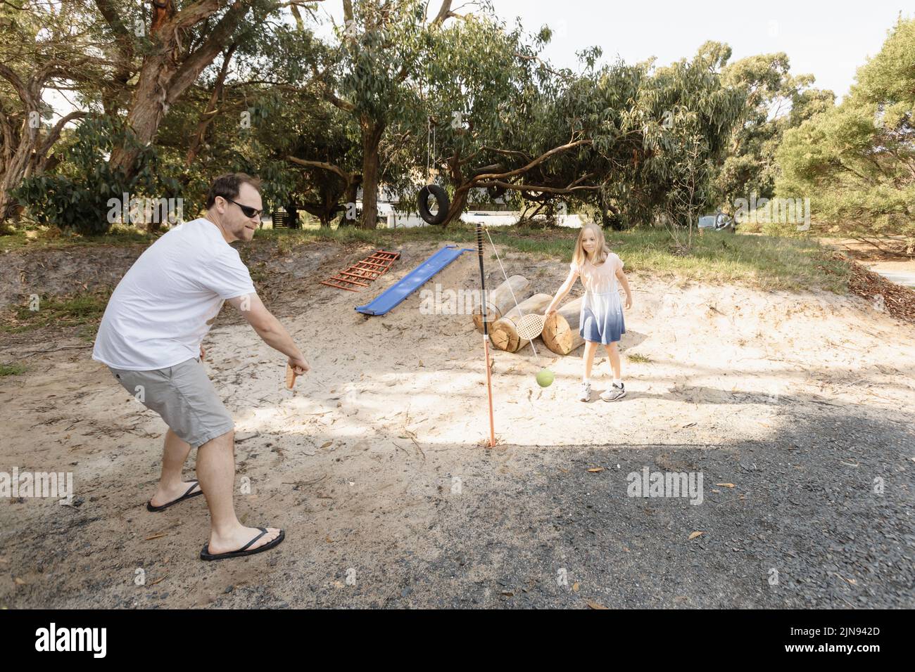 Un padre australiano che gioca a totem tennis nel loro cortile con sua figlia Foto Stock