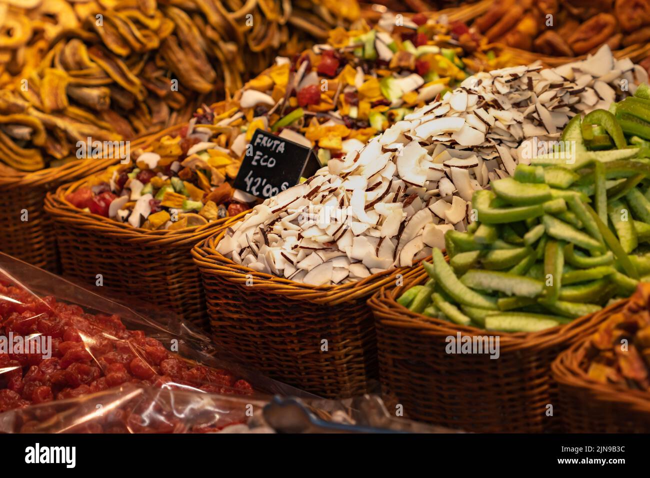 Avocado, cocco e altre frutta a fette in un cestino di vimini al mercato Boqueria di Barcellona (Spagna). Foto Stock