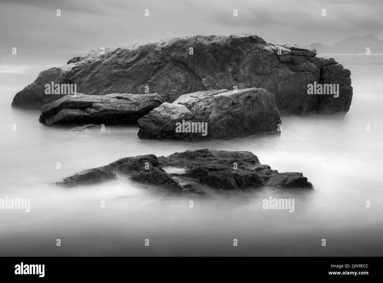 Mare liscio e setoso intorno alle rocce con una lunga esposizione. Foto Stock