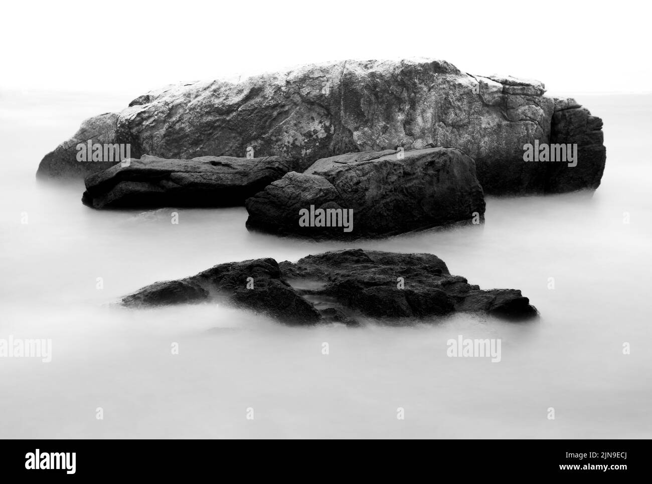 Mare liscio e setoso intorno alle rocce con una lunga esposizione. Foto Stock