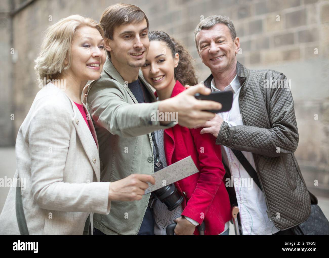 Turisti che prendono selfie sulla vecchia strada della città europea Foto Stock