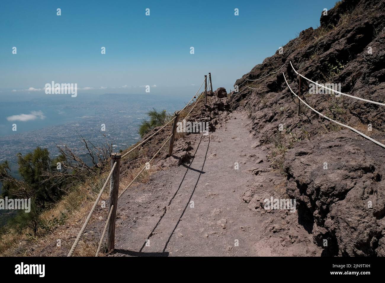 Il percorso intorno alla cima del cono del Vesuvio con la vista mozzafiato sulla zona di Napoli a sinistra. Foto Stock