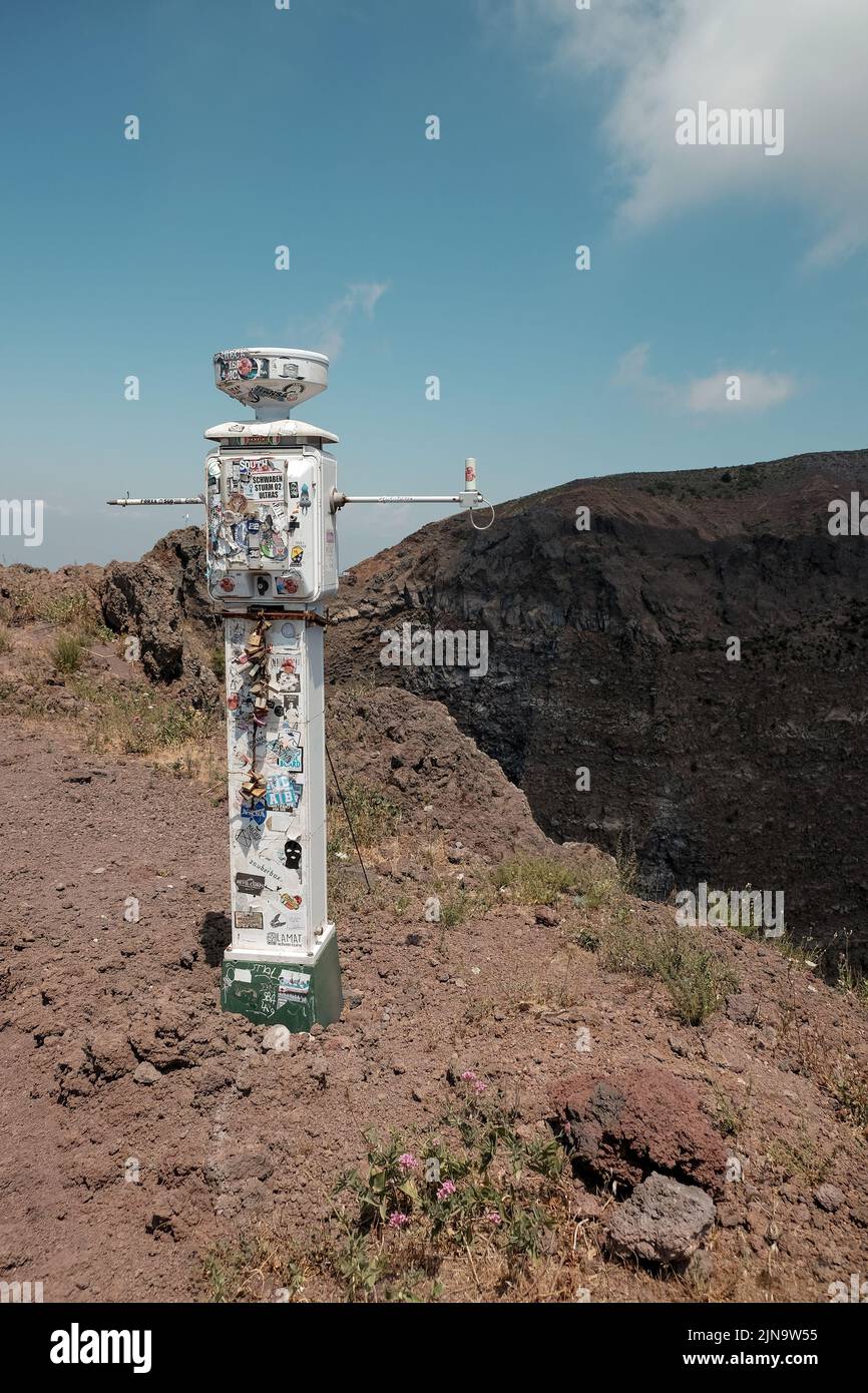 Lucchetti d'amore e adesivi turistici su uno strumento di misura scientifico sul Vesuvio sul bordo del cratere del vulcano attivo in Italia. Foto Stock