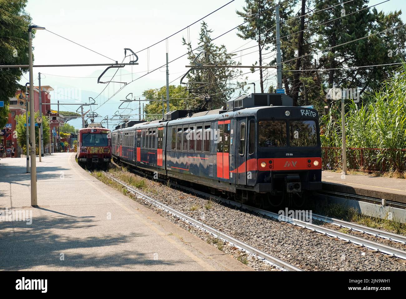Due treni in entrata - in uscita alla stazione ferroviaria di Pompei. I treni viaggiano da Sorrento a Napoli fermandosi in luoghi turistici lungo il tragitto. Foto Stock