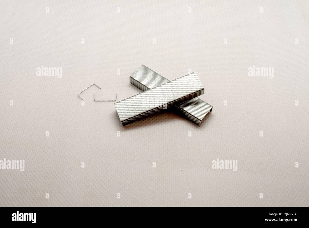 Punti metallici per la cucitrice: Una foto scattata su alcuni punti metallici da utilizzare per una cucitrice su sfondo bianco. Foto Stock