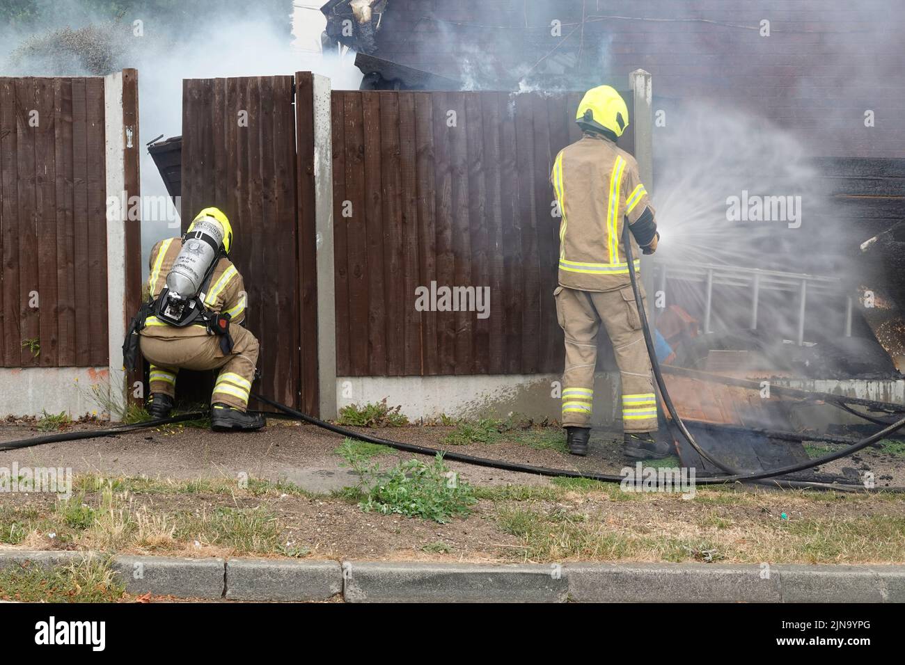 Servizio antincendio e di soccorso Essex vigili del fuoco in abbigliamento protettivo lavoro pericoloso e pericoloso su fuoco domestico che lavora con respiratore Inghilterra UK Foto Stock