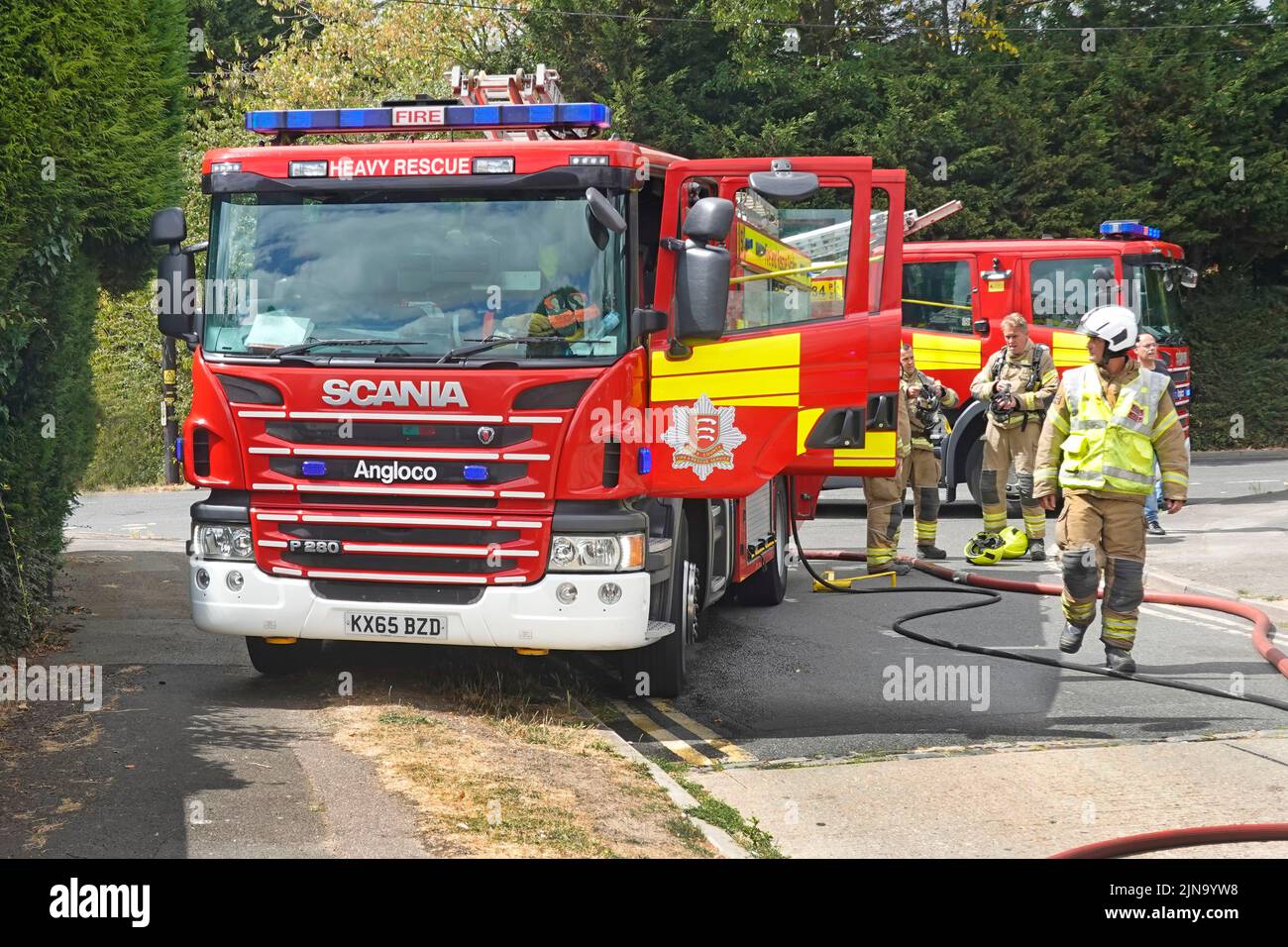 Servizio antincendio e di soccorso Essex vigili del fuoco vigili del fuoco presenti in casa con due motori antincendio e vigili del fuoco in via residenziale Inghilterra Regno Unito Foto Stock