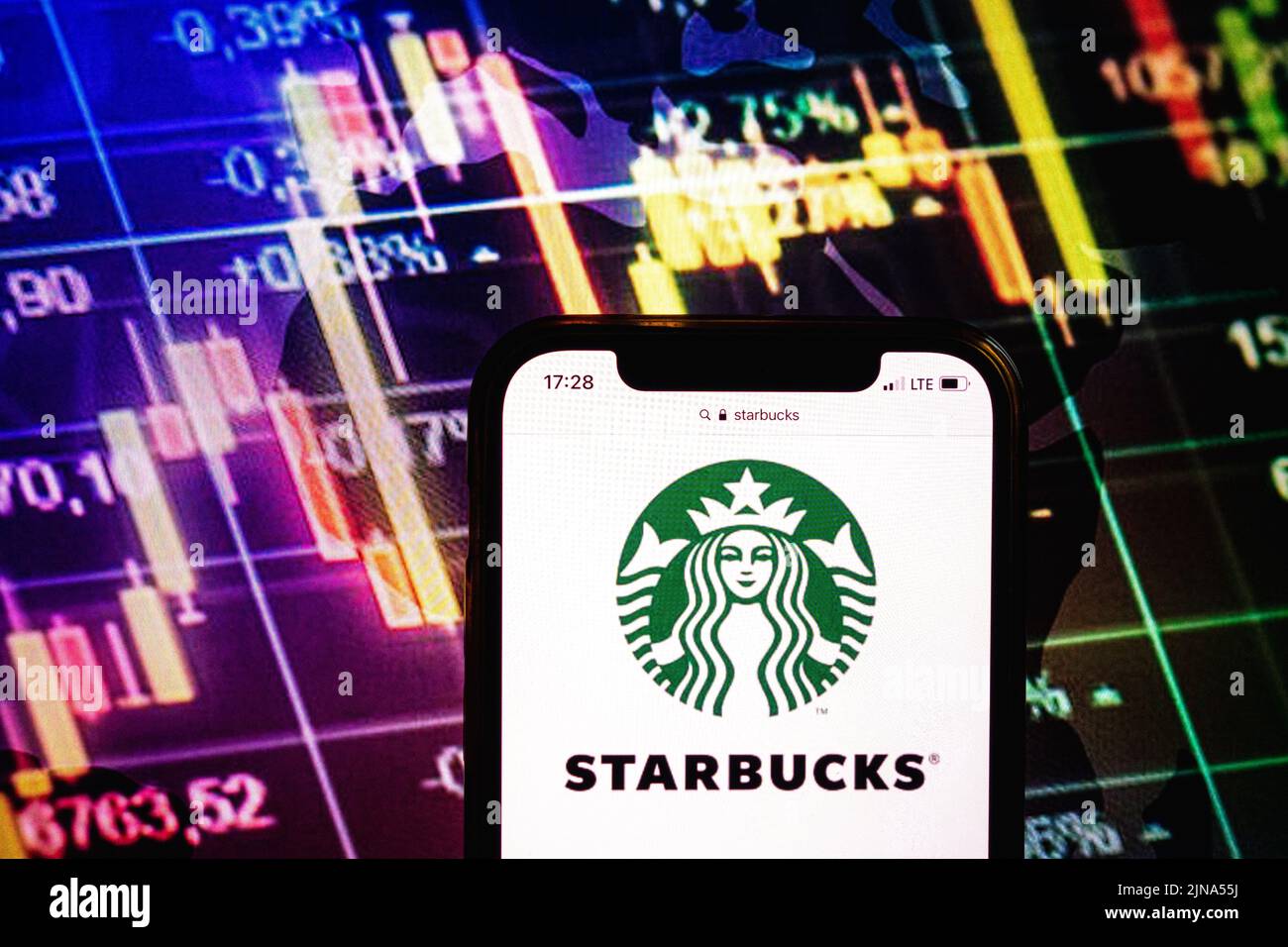 KONSKIE, POLONIA - 09 agosto 2022: Smartphone che mostra il logo della società Starbucks sullo sfondo del diagramma di borsa Foto Stock
