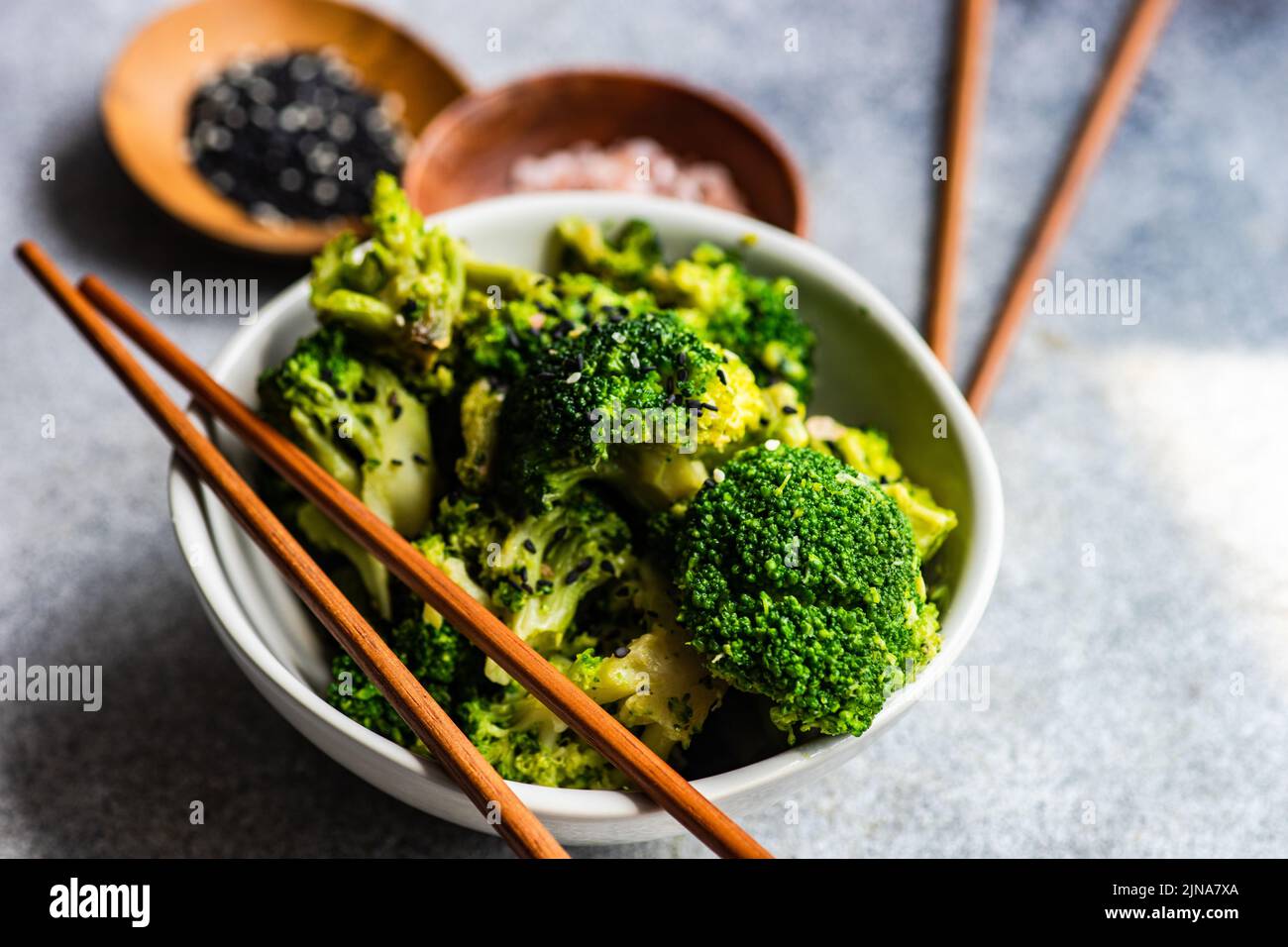 Primo piano di una ciotola di broccoli con semi di sesamo e sale rosa dell'himalaya Foto Stock