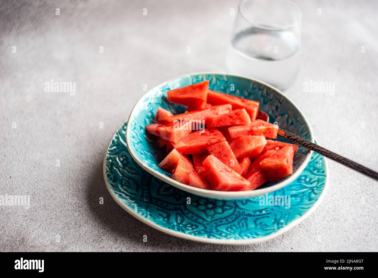 Ciotola di melone tritato con un bicchiere d'acqua Foto Stock