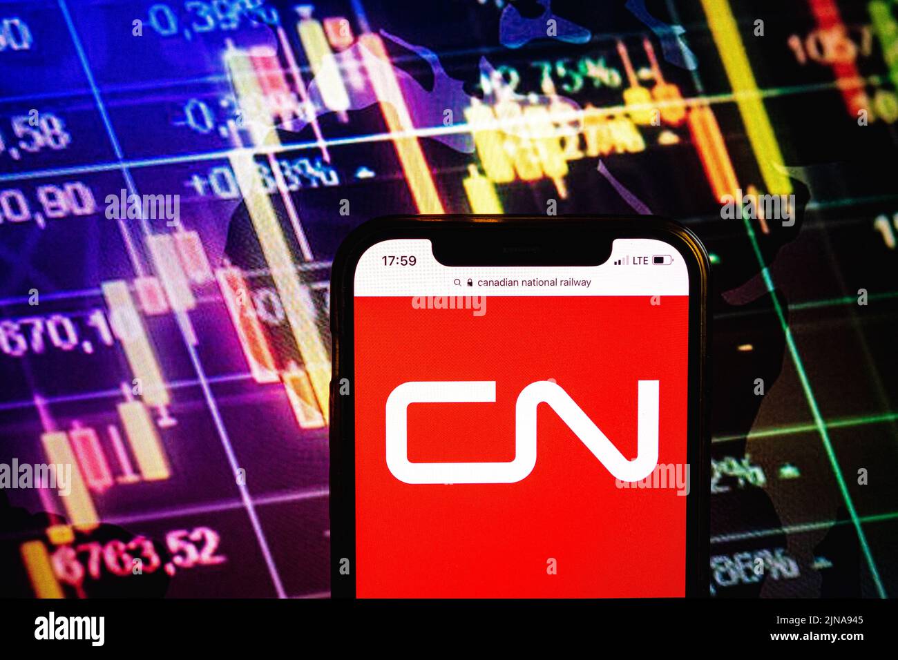KONSKIE, POLONIA - 09 agosto 2022: Smartphone che mostra il logo della compagnia ferroviaria nazionale canadese sullo sfondo del diagramma di borsa Foto Stock