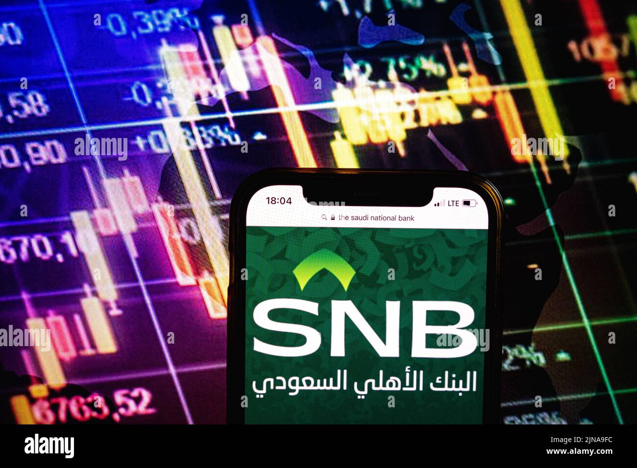 KONSKIE, POLONIA - 09 agosto 2022: Smartphone che mostra il logo della società della Banca Nazionale Saudita sullo sfondo del diagramma di borsa Foto Stock