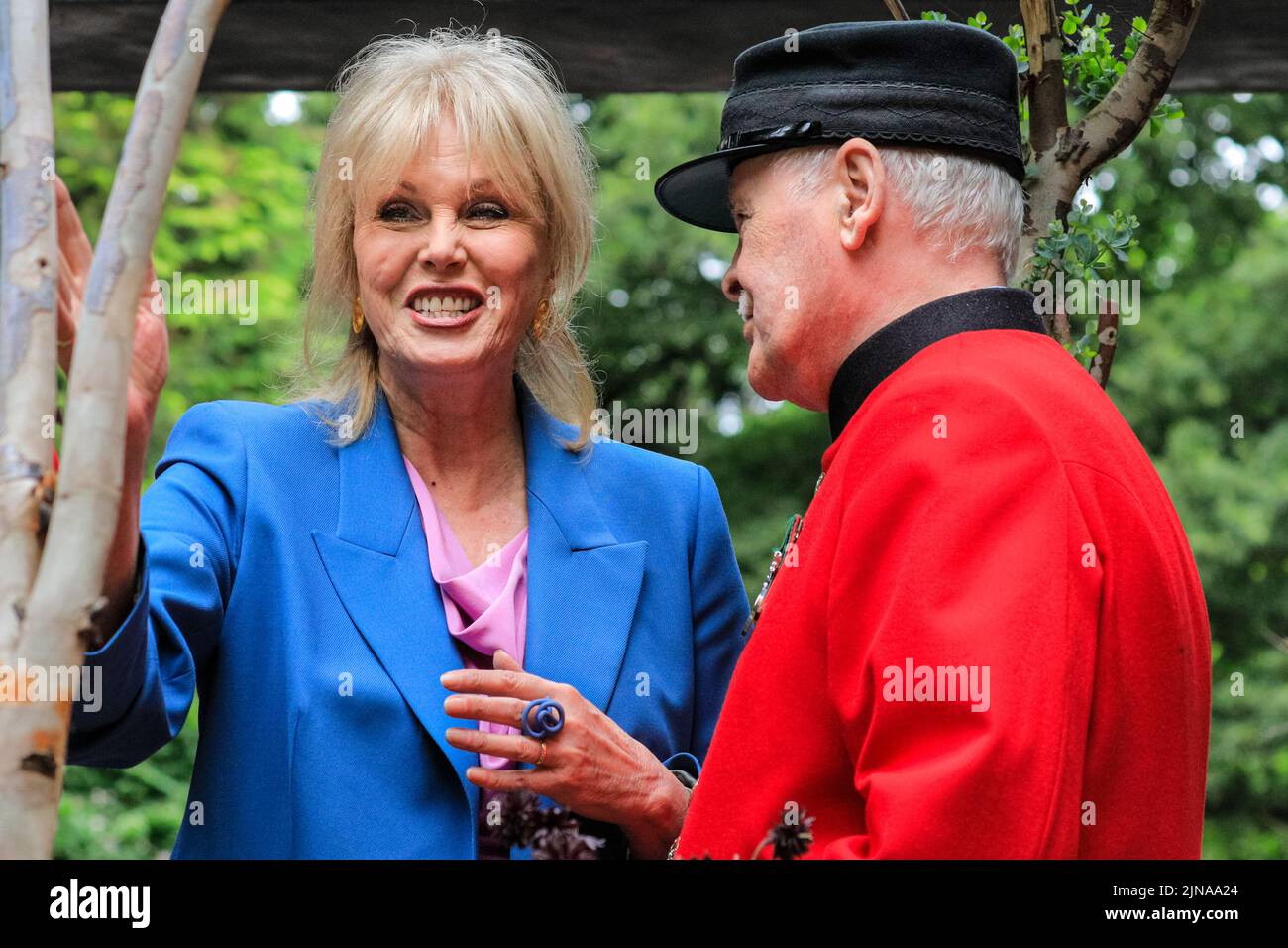 L'attrice Joanna Lumley sorridendo, da vicino, si pone con il pensionato Chelsea John Gallagher nelle sue uniformi rosse, Chelsea Flower Show 2022 Foto Stock