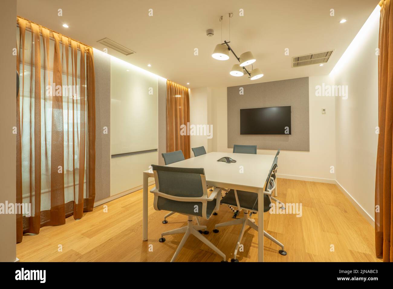 Sala riunioni di un ufficio professionale con tv a parete e sedie bianche girevoli Foto Stock