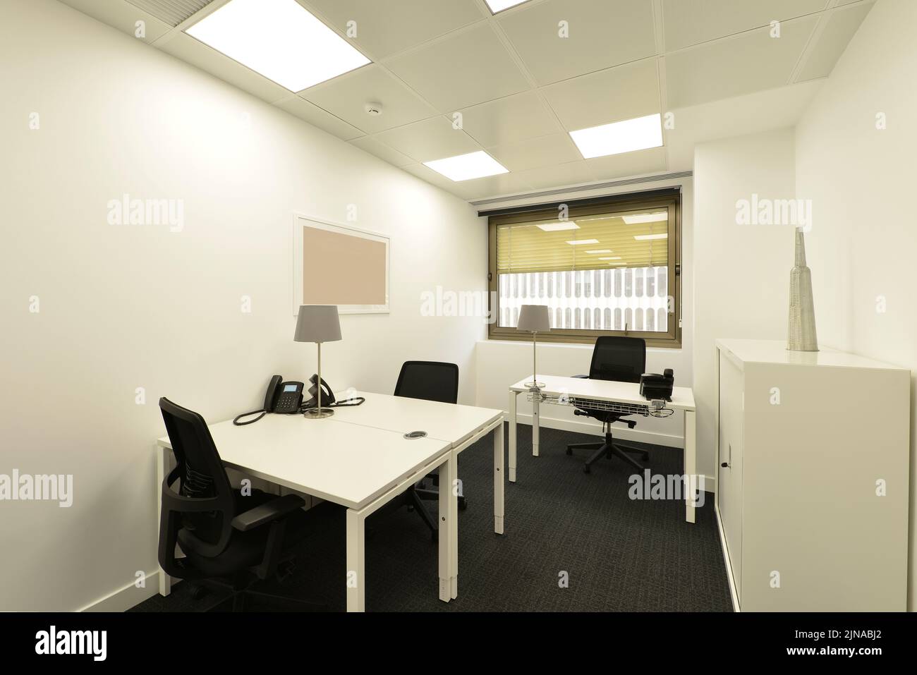 Cabina in ufficio professionale con tavolo condiviso, lima, sedie girevoli nere Foto Stock