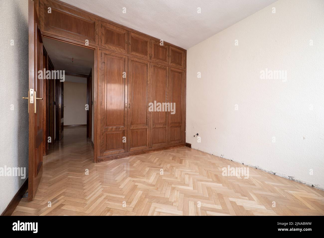 Camera da letto vuota con parquet di quercia a spina di pesce, armadi a muro e bauli completamente a copertura della parete Foto Stock