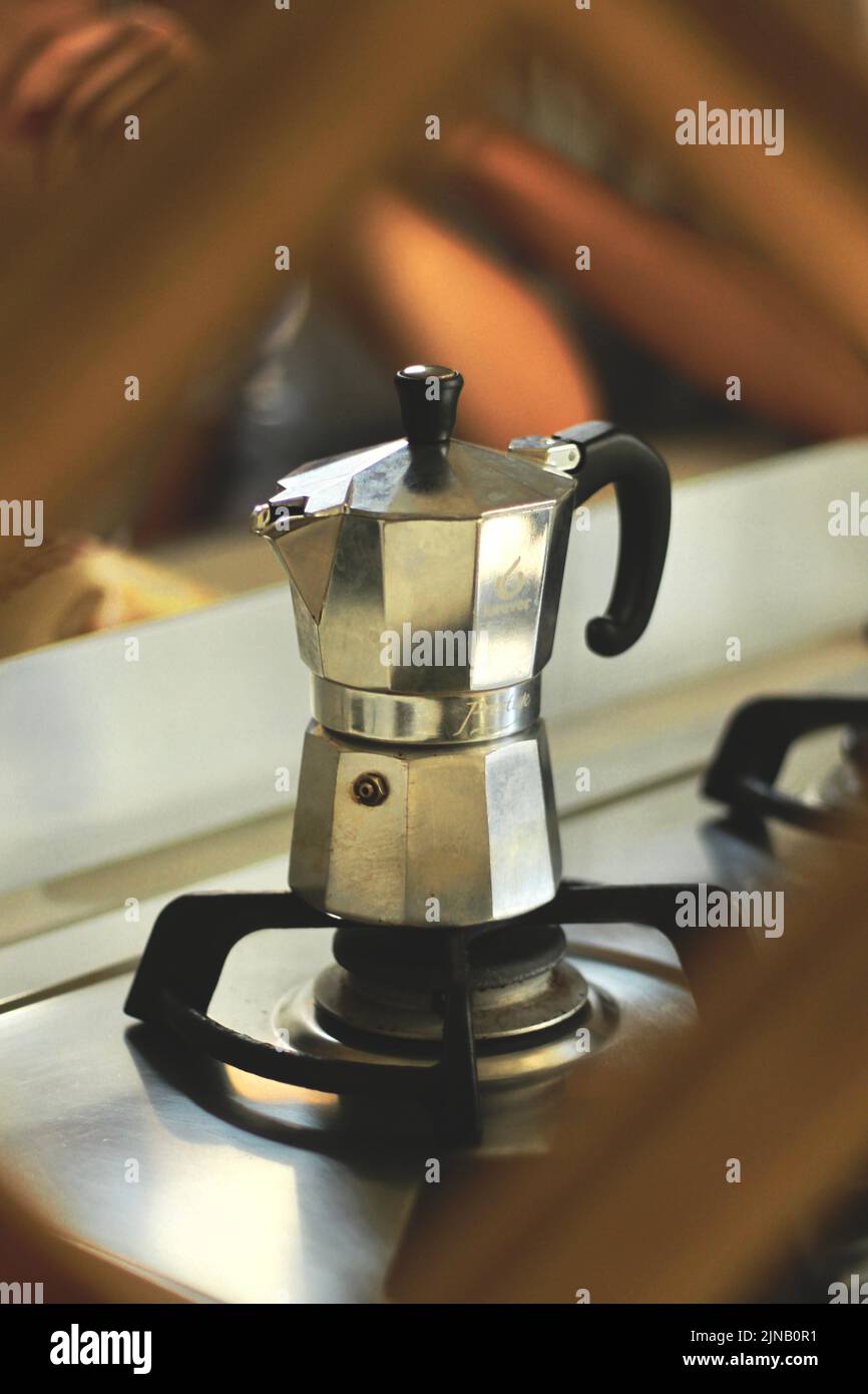Primo piano di una caffettiera italiana su un fornello con un ramé in primo piano. Foto Stock