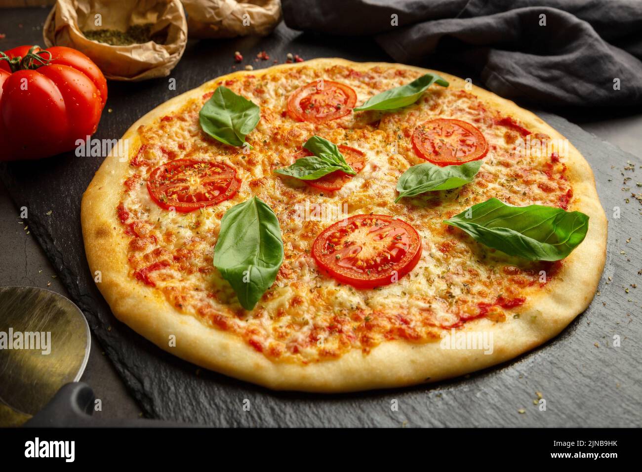 Pizza intera sul tavolo con ingredienti Foto Stock