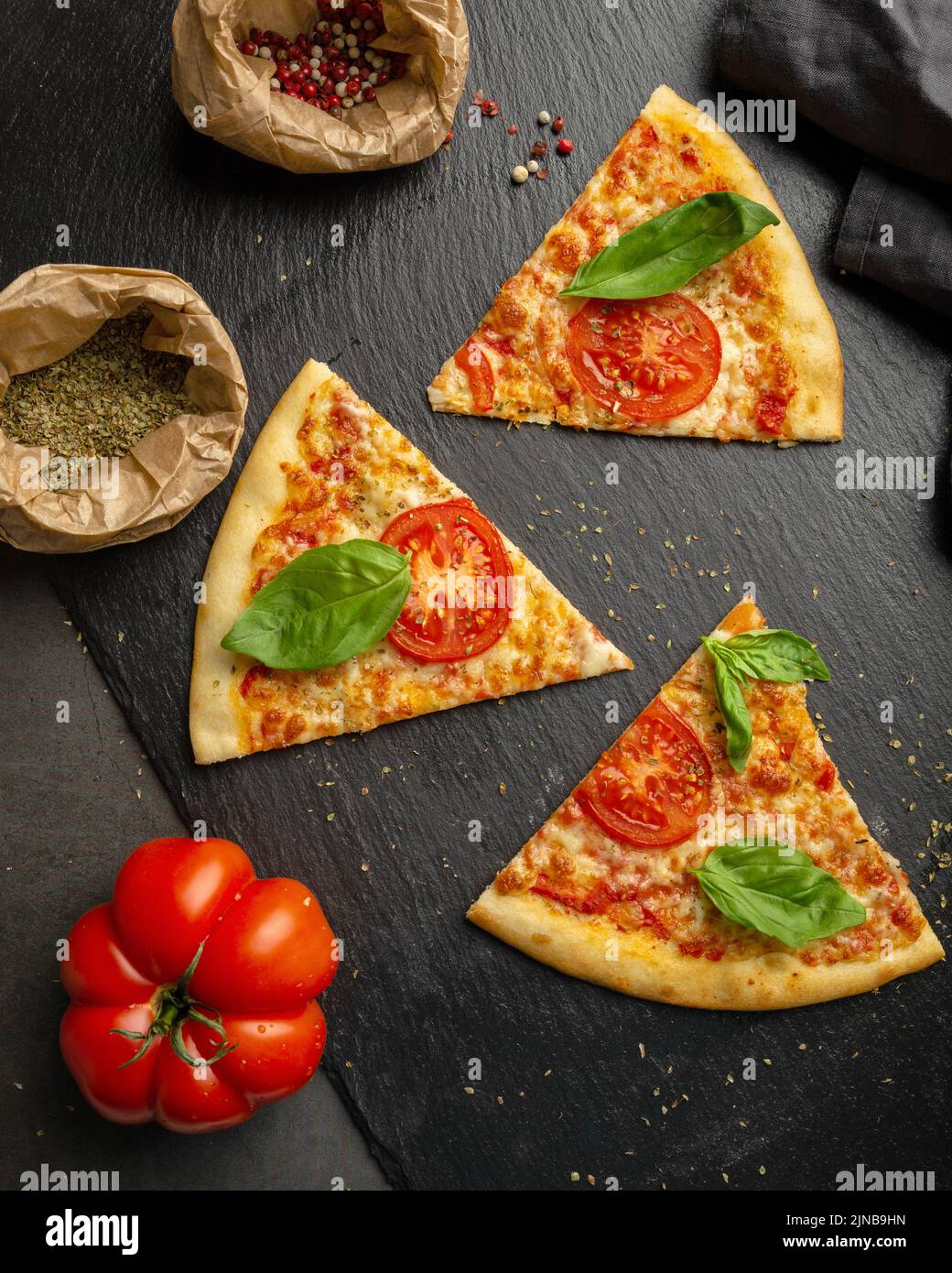 Pezzi di pizza sul tavolo con ingredienti Foto Stock