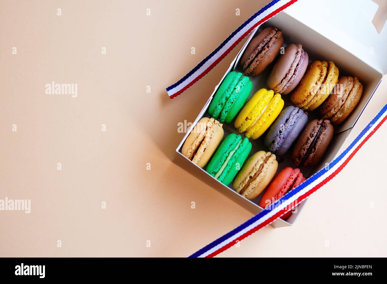 Macaroni assortiti in scatola di torta decorata con nastro di colori bandiera francese Foto Stock