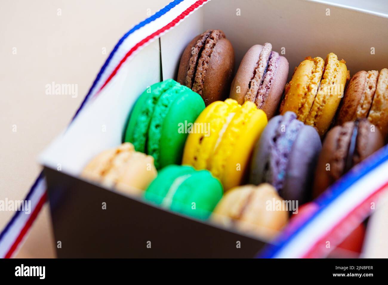Macaroni assortiti in scatola di torta decorata con nastro di colori bandiera francese Foto Stock
