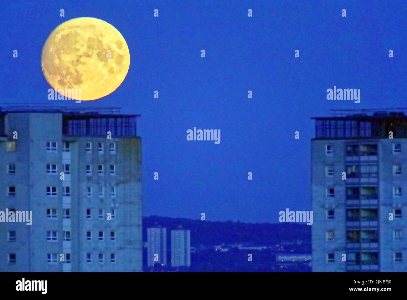 Glasgow, Scozia, Regno Unito 10th agosto 2022. UK Meteo: Tempo soleggiato ha visto una quasi piena luna di sturgeon yje ultima super luna dell'anno salire sopra le torri del consiglio di Knightswood con la tenuta di castlemilk in lontananza. Credit Gerard Ferry/Alamy Live News Foto Stock