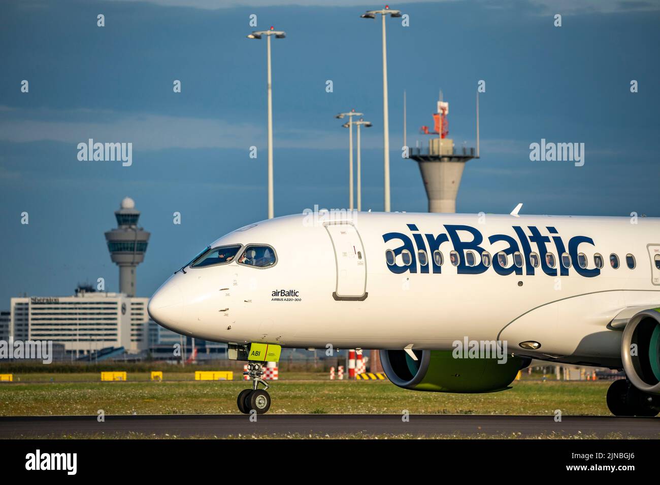 Aeroporto di Amsterdam Shiphol, Ponderbaan, una delle 6 piste, torre di controllo del traffico aereo, in taxi per decollo, airBaltic, Airbus A220 Foto Stock