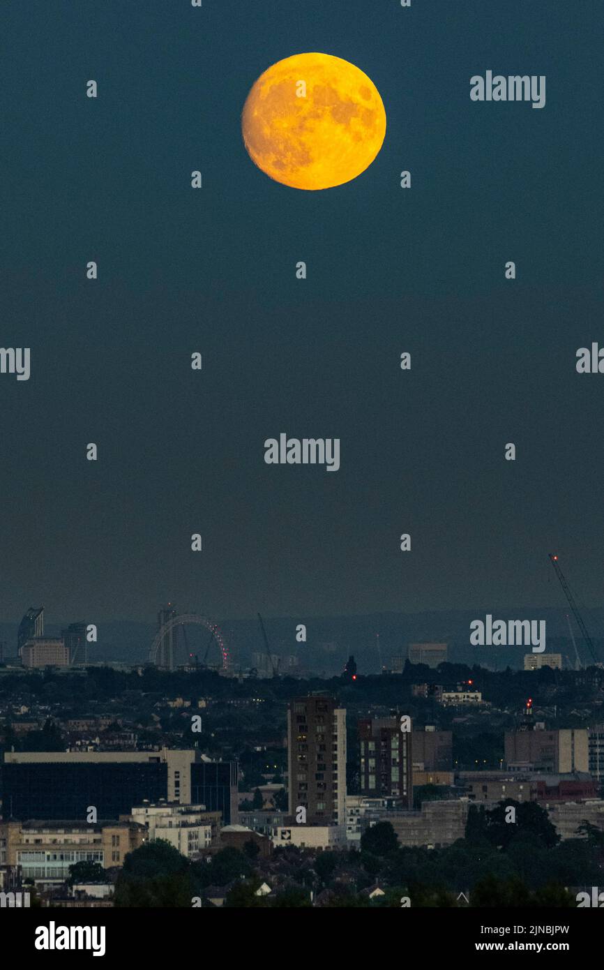 Londra, Regno Unito. 10 agosto 2022. Tempo del Regno Unito – una luna gibbosa del 97,1% si innalza attraverso uno strato di smog sopra il London Eye e lo skyline della capitale. Secondo l’Almanac dell’Old Farmer, la luna piena di agosto (alle 02:35 del 12 agosto) è chiamata la Luna dello storione a causa del gran numero di pesci storione che si sono trovati nei grandi Laghi del Nord America in questo periodo dell’anno. La luna piena di agosto è nota anche come “luna piena” che appare più luminosa e più grande in quanto sarà nel suo punto più vicino alla Terra nella sua orbita, conosciuta come il perigee. Credit: Stephen Chung / Alamy Live News Foto Stock