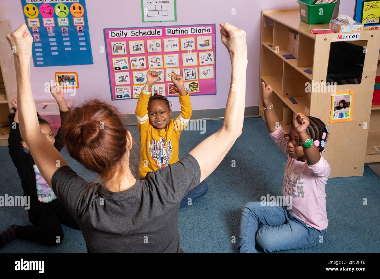 Istruzione Preschool cura dei bambini dai 4 anni in su insegnante di yoga che lavora con un piccolo gruppo di ragazze Foto Stock