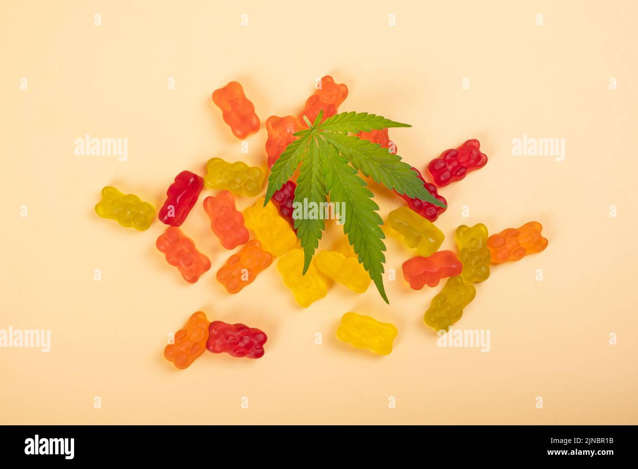 caramelle di gelatina di thc, dolci di cannabis e foglia verde su sfondo giallo. Foto Stock