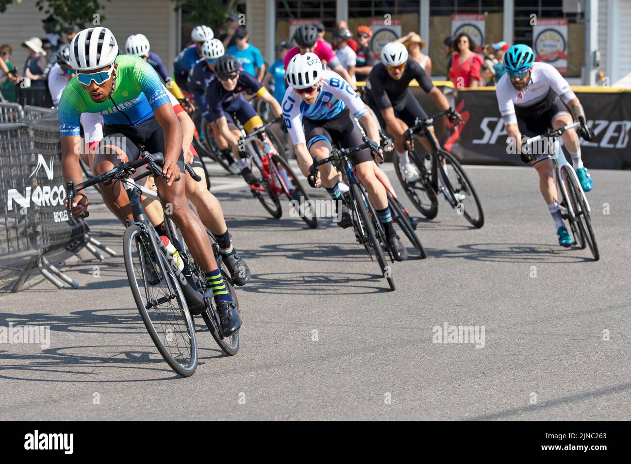 Ciclisti in un peloton che cavalca un giro del Criterium, una gara veloce in bicicletta dove i ciclisti guidano le loro biciclette intorno ad un circuito sulle strade della città Foto Stock Ciclisti in un peloton che cavalca un giro del Criterium, una gara veloce in bicicletta dove i ciclisti guidano le loro biciclette intorno ad un circuito sulle strade della città Foto Stock