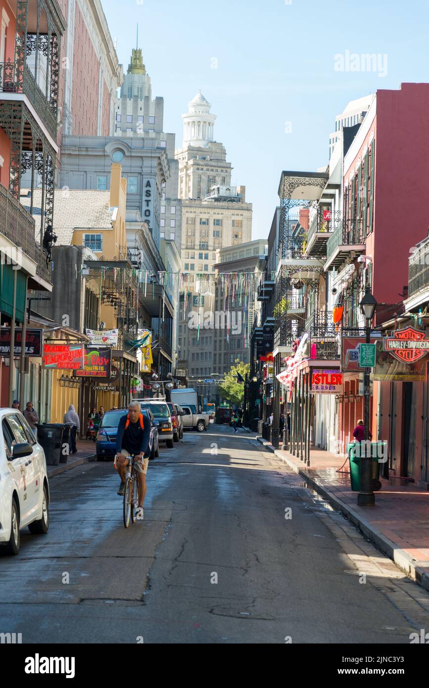 L'uomo guida la sua bicicletta lungo Bourbon St. New Orleans Foto Stock