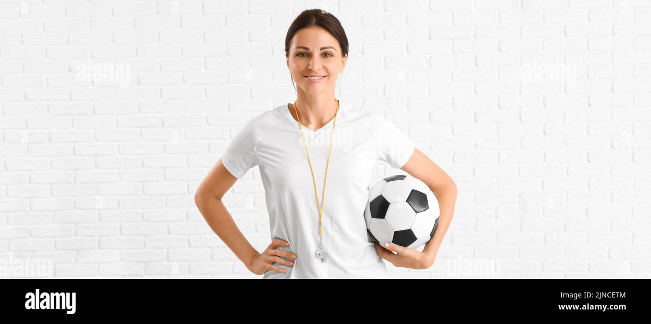 Insegnante di educazione fisica femminile con palla su sfondo di mattoni bianchi Foto Stock