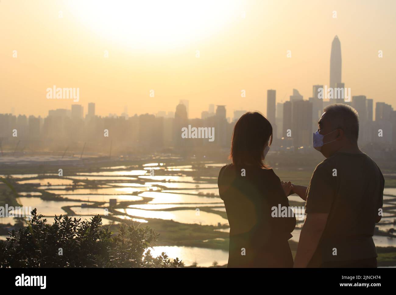 il vecchio ama e guarda il tramonto di fronte allo skyline della città Foto Stock