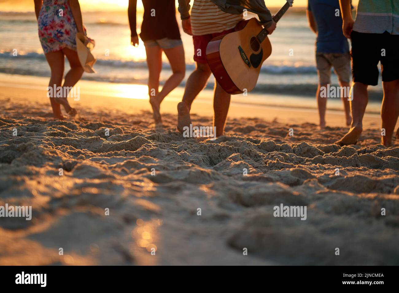Lasciate che la sabbia si strinca sotto i vostri piedi... Ripresa da dietro di un gruppo di amici irriconoscibili che camminano insieme sulla spiaggia. Foto Stock