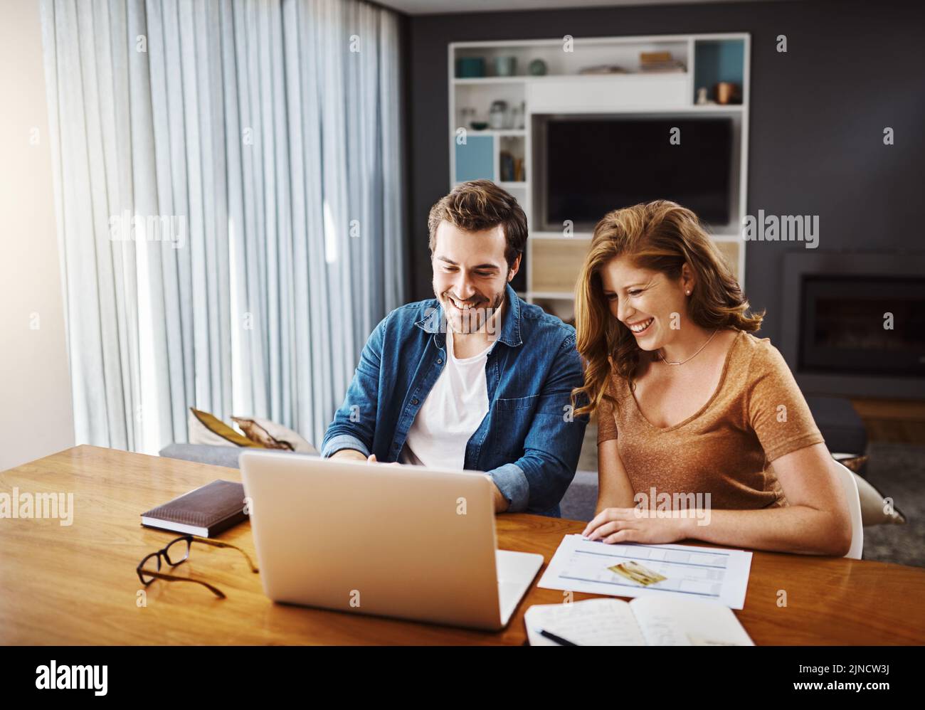 Collaborando per fare le migliori scelte finanziarie. Una giovane coppia che guarda i video online insieme mentre fa il loro budget mensile a casa. Foto Stock