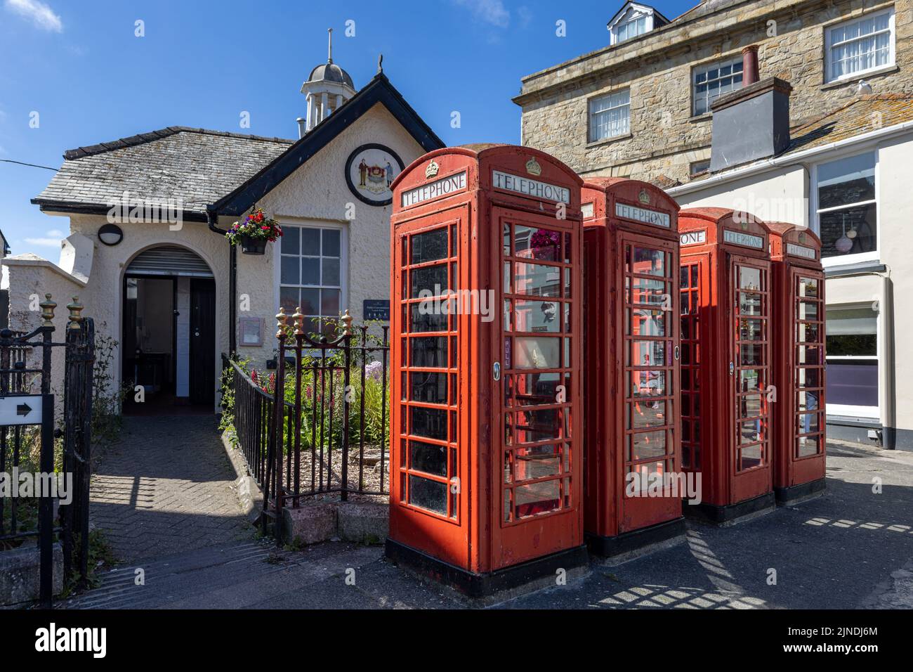 Fila di quattro tradizionali cabine telefoniche rosse all'esterno dei bagni pubblici nel centro di Truro, Cornovaglia. Foto Stock