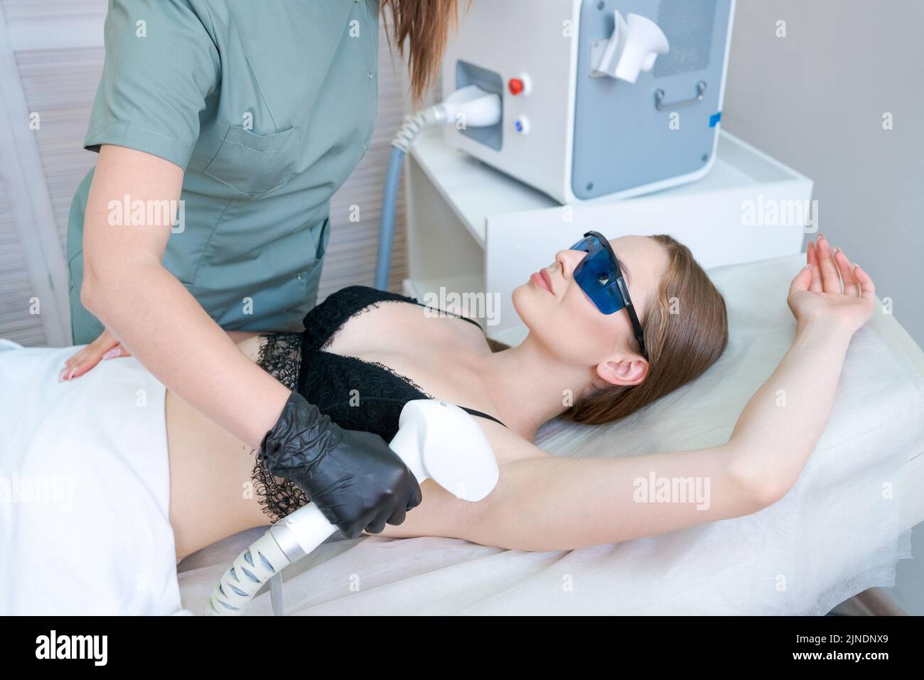 Cliente felice su procedura di rimozione dei capelli del laser sul corpo in un salone di bellezza, si trova sul divano. Foto Stock