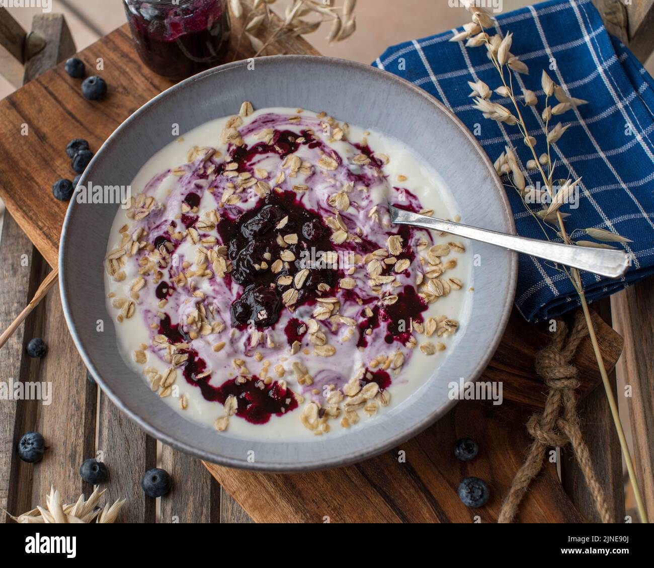 Yogurt per la colazione con composta di mirtilli e fiocchi di avena in una ciotola con cucchiaio Foto Stock