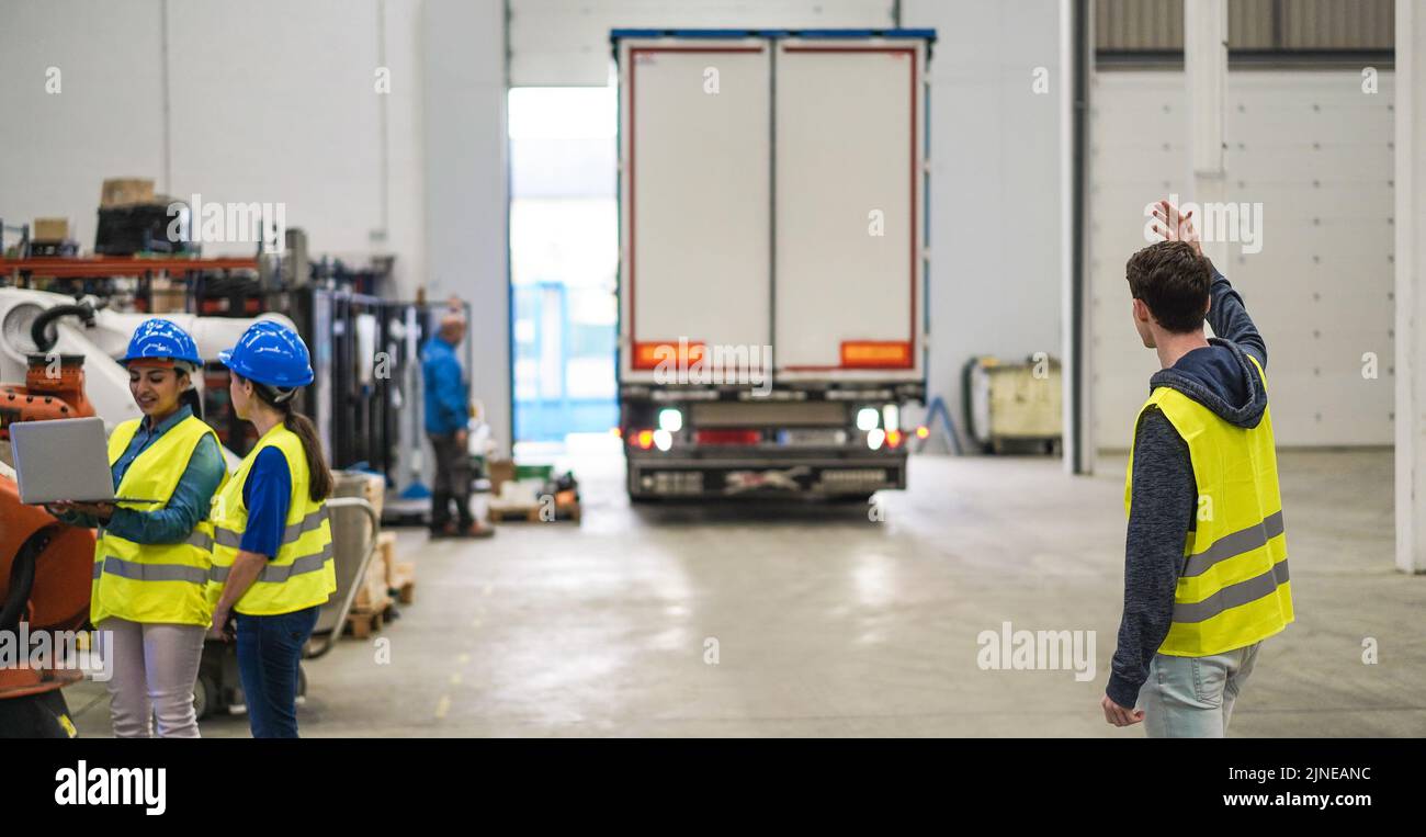 Ingegneri multietnici che lavorano all'interno di una fabbrica robotica - concentratevi sulla parte posteriore destra dell'uomo Foto Stock