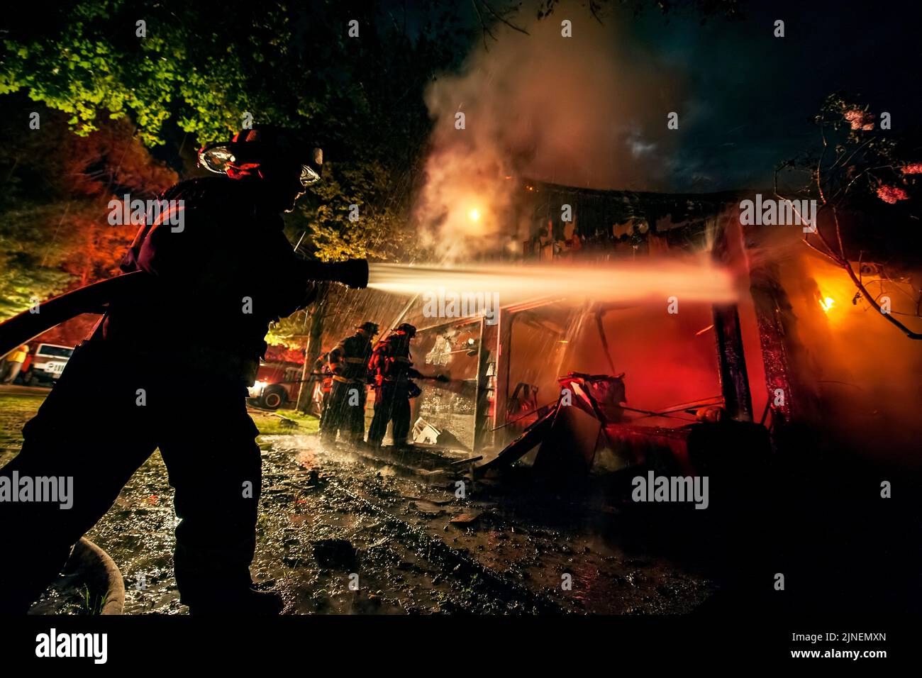 Un vigile del fuoco è sileted mentre allena il suo flusso di manichetta sui punti caldi come alle 10:16:00 pm il mercoledì 18th maggio 2016 il reparto di fuoco di Sag Harbor wa Foto Stock