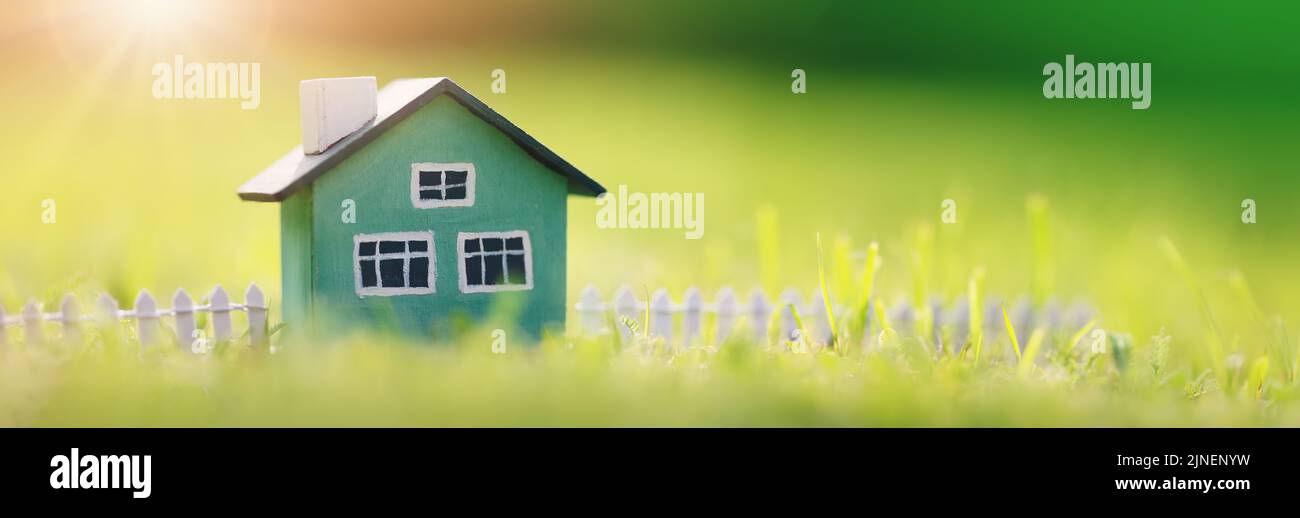 Modello di casa verde con recinzione in piedi sull'erba verde Foto Stock