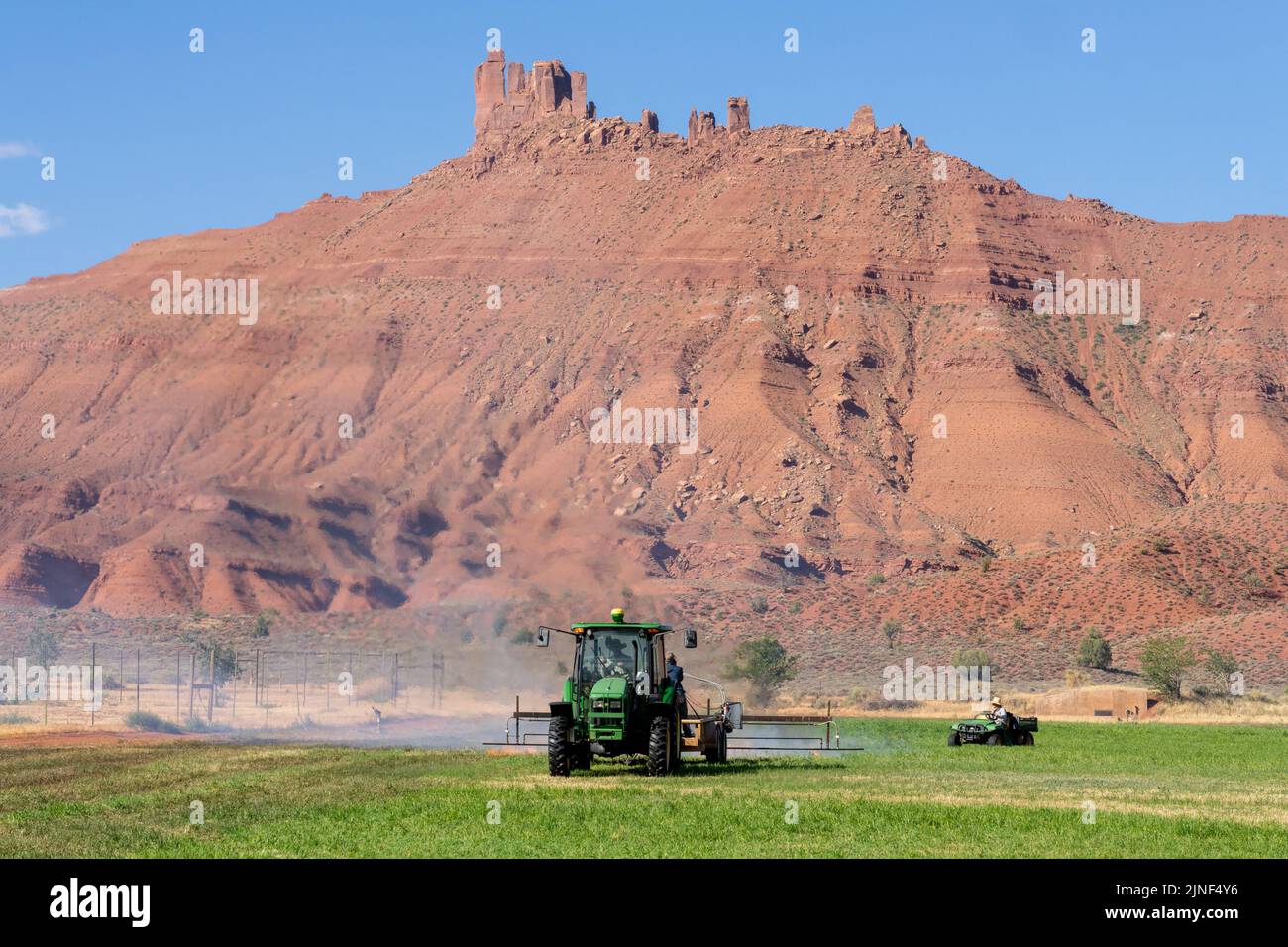 Un trattore che tira un bruciatore a propano brucia le erbacce in un hayfield dopo aver tagliato l'erba medica su un ranch nello Utah. Foto Stock