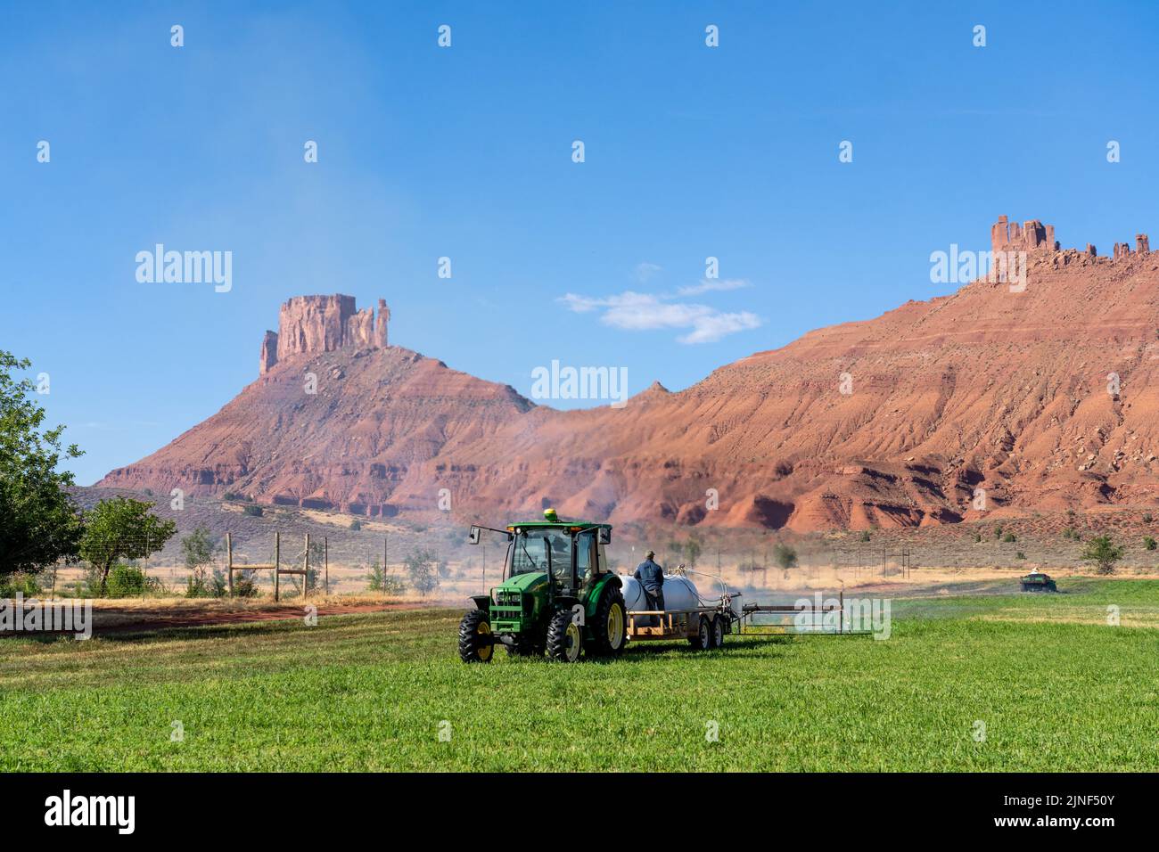 Un trattore che tira un bruciatore a propano brucia le erbacce in un hayfield dopo aver tagliato l'erba medica su un ranch nello Utah. Foto Stock