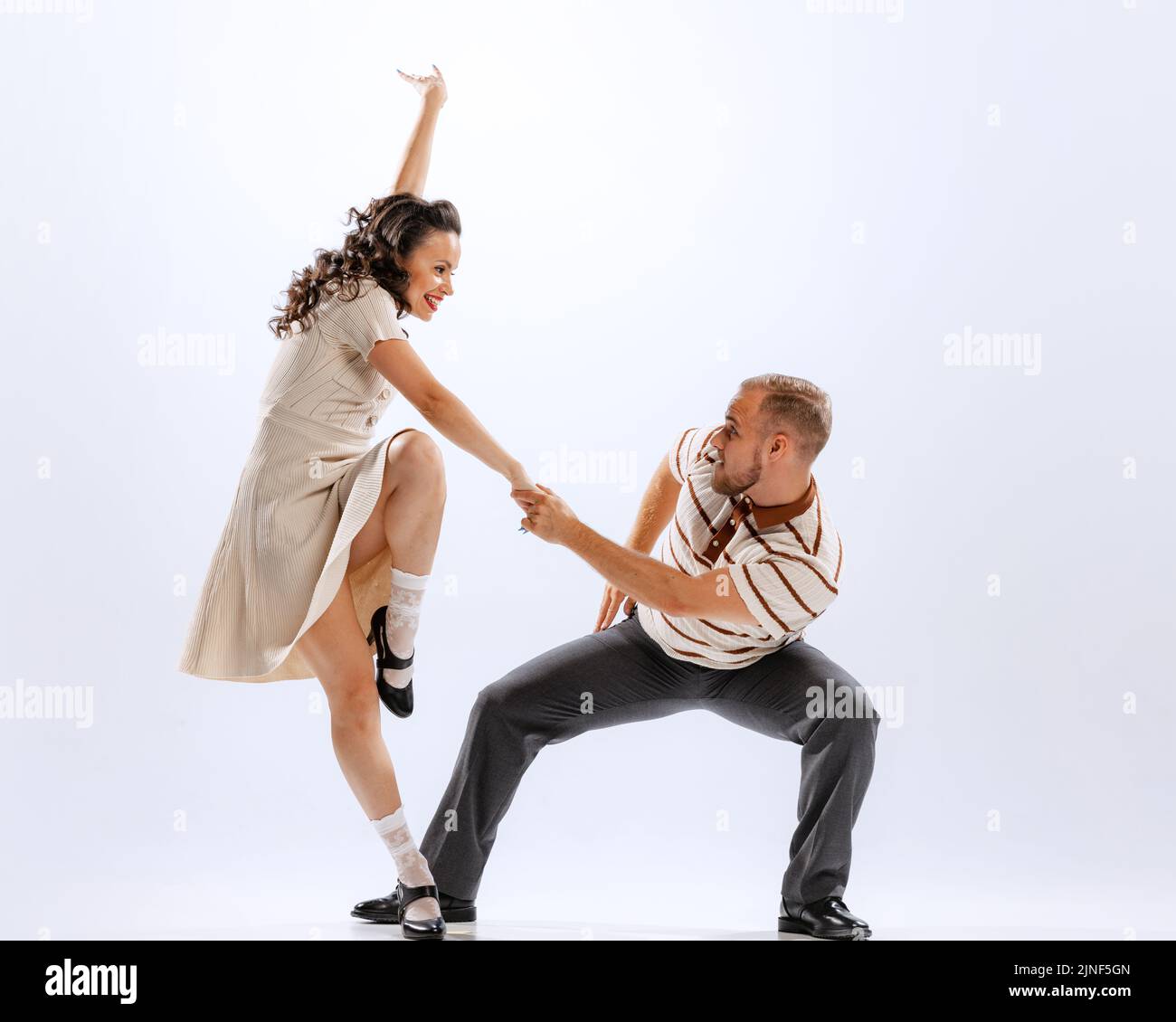 Ritratto dinamico di danza emotiva uomo e donna sport balli isolati su sfondo bianco. 50s, 60s, 70s stile di moda americano. Foto Stock