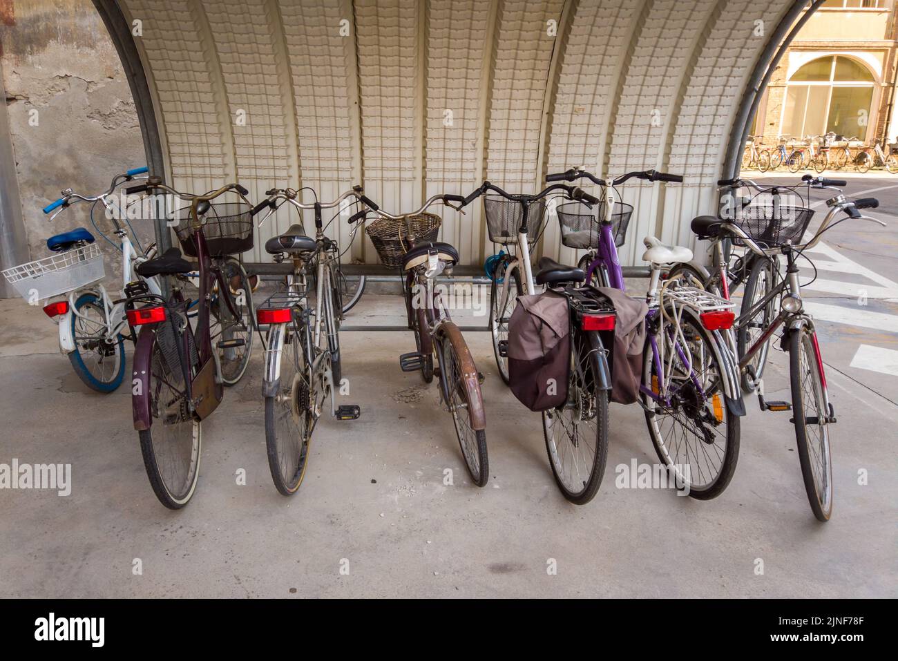 Biciclette parcheggiate sotto la tettoia, biciclette con cesto e borse Foto Stock