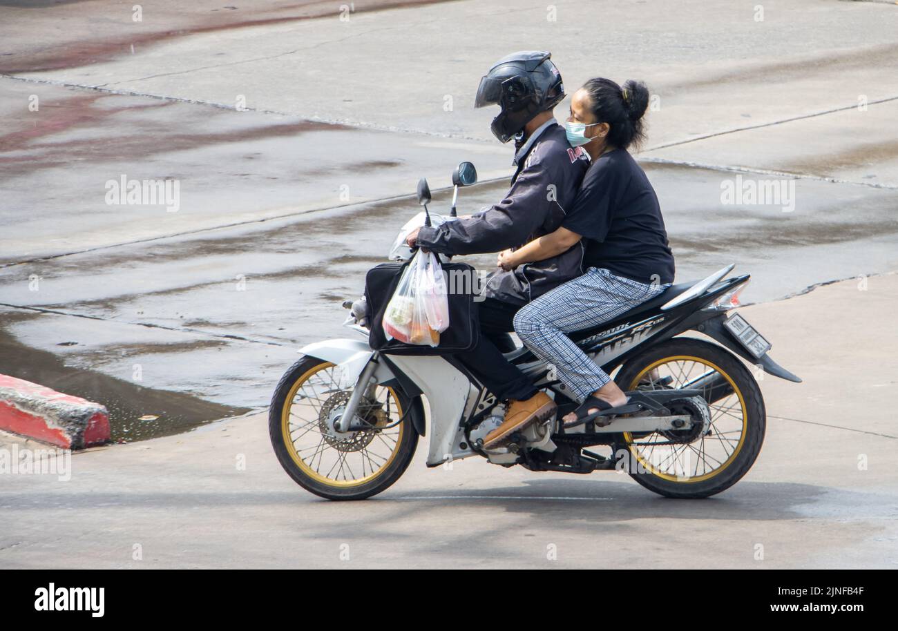 SAMUT PRAKAN, THAILANDIA, 28 2022 MAGGIO, la coppia cavalca in moto sulla strada bagnata. Foto Stock