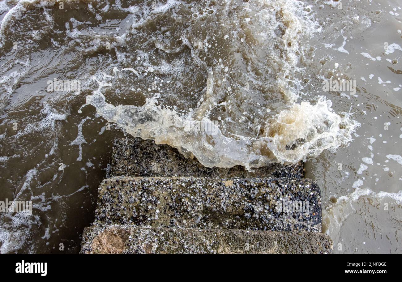 Onde di mare tempestose che si infrangono contro scale di pietra, vista dall'alto. Foto Stock